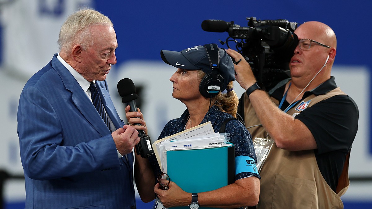 Cowboys owner Jerry Jones speaks into a handheld microphone during a sideline interview before kickoff.