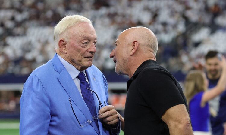 Cowboys owner Jerry Jones, in a light blue suit, talks with Jeff Bezos on the field before kickoff.