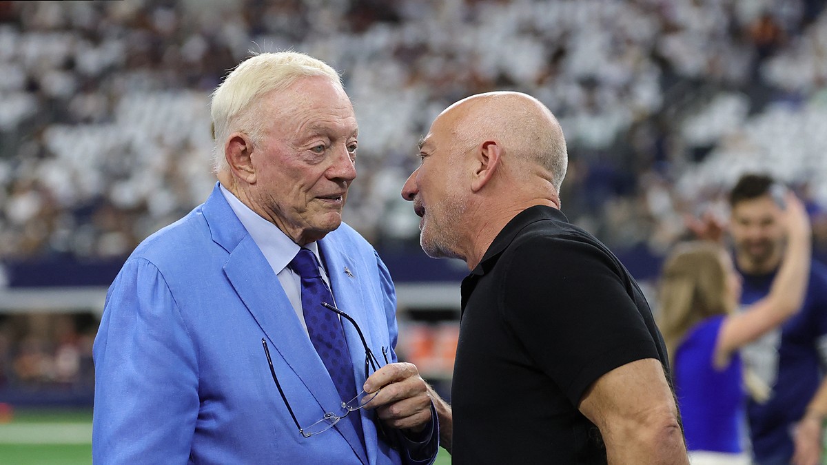Cowboys owner Jerry Jones, in a light blue suit, talks with Jeff Bezos on the field before kickoff.