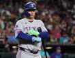 Rangers designated hitter Joc Pederson stands at the plate adjusting his batting gloves after a call.