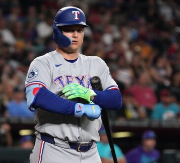 Rangers designated hitter Joc Pederson stands at the plate adjusting his batting gloves after a call.
