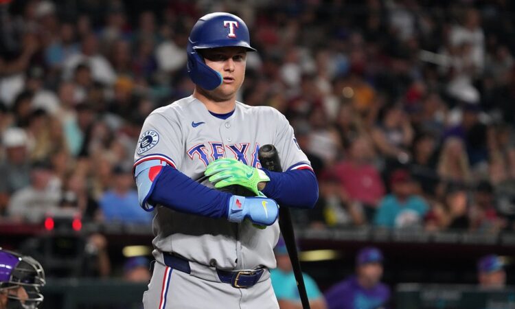 Rangers designated hitter Joc Pederson stands at the plate adjusting his batting gloves after a call.