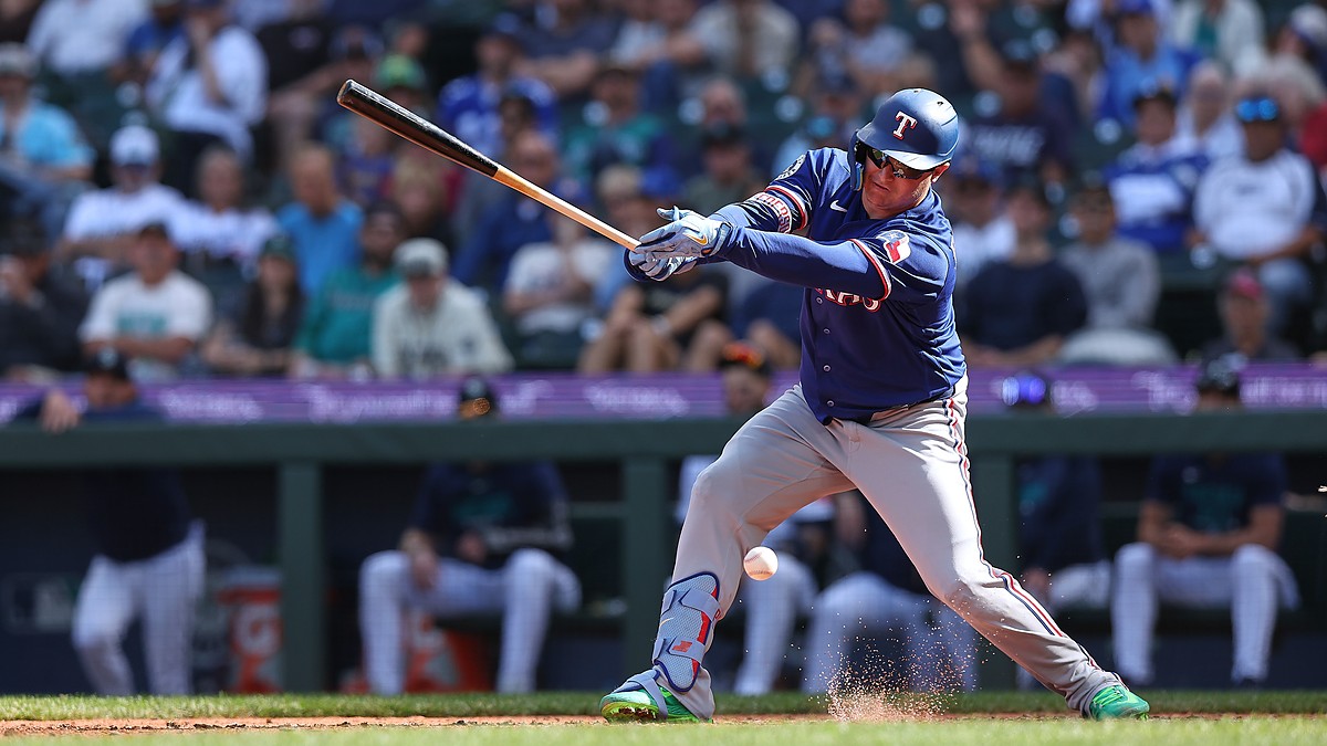 Texas Rangers designated hitter Joc Pederson swings as the ball bounces near his shin guard and dirt sprays at his feet.