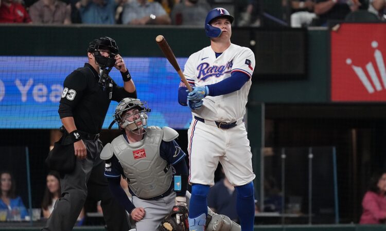 Texas Rangers first baseman Joc Pederson watches his home run as Tampa Bay Rays catcher Liam Hicks and the umpire look up.