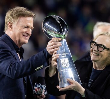 NFL commissioner Roger Goodell hands the Vince Lombardi Trophy to Seattle Seahawks chairman Jody Allen on the podium.