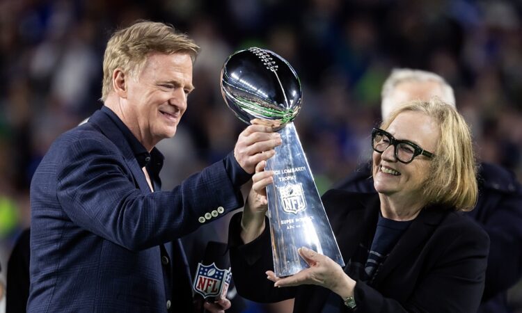 NFL commissioner Roger Goodell hands the Vince Lombardi Trophy to Seattle Seahawks chairman Jody Allen on the podium.