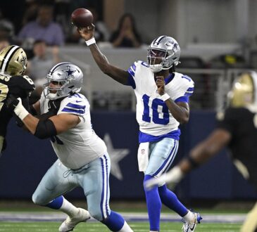 Dallas Cowboys quarterback Joe Milton III releases a pass as a Saints lineman raises an arm in front of him.