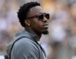 Steelers cornerback Joey Porter Jr. watches from the sideline in a hooded sweatshirt and sunglasses.
