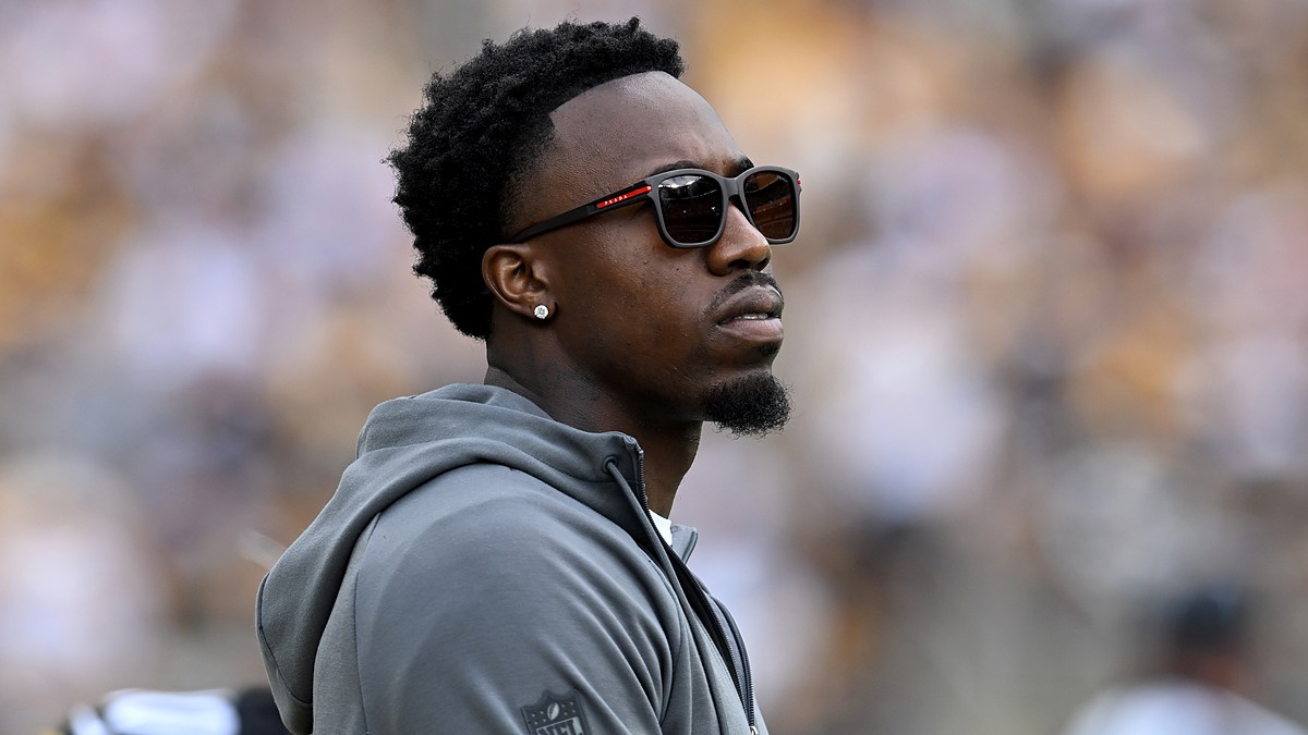 Steelers cornerback Joey Porter Jr. watches from the sideline in a hooded sweatshirt and sunglasses.