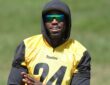 Steelers cornerback Joey Porter Jr. smiles in a hooded practice jersey while watching camp drills.