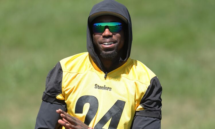 Steelers cornerback Joey Porter Jr. smiles in a hooded practice jersey while watching camp drills.