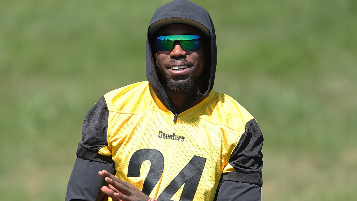 Steelers cornerback Joey Porter Jr. smiles in a hooded practice jersey while watching camp drills.
