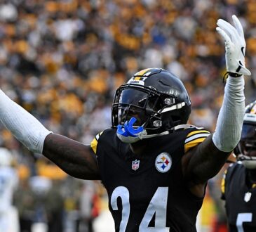 Pittsburgh Steelers cornerback Joey Porter Jr. raises both arms in celebration as teammates react behind him.