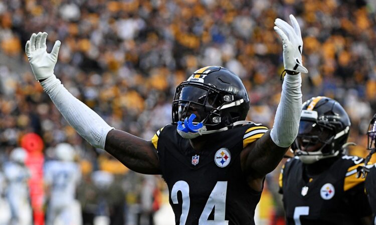 Pittsburgh Steelers cornerback Joey Porter Jr. raises both arms in celebration as teammates react behind him.