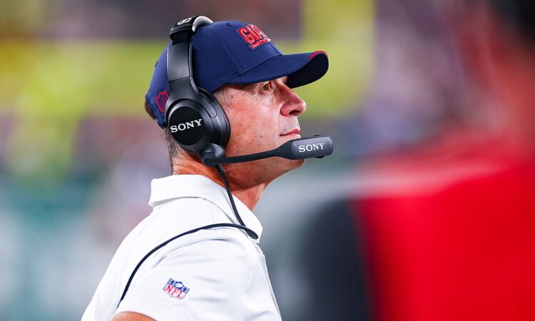 New York Giants head coach John Harbaugh looks up from the sideline wearing a headset during a game against the Jets.