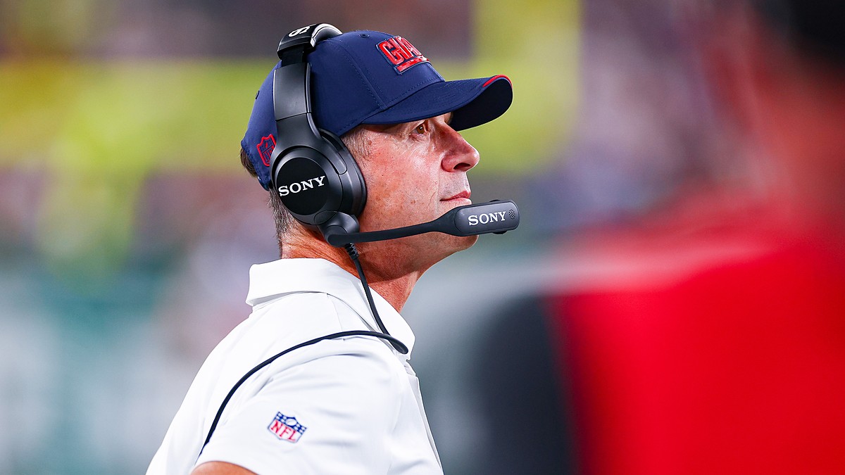 New York Giants head coach John Harbaugh looks up from the sideline wearing a headset during a game against the Jets.