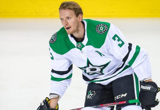 Dallas Stars defenseman John Klingberg, helmetless and wearing an alternate captain’s A, skates with his stick during warmups.