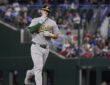 Athletics catcher Jonah Heim raises a hand toward the stands while rounding the bases after a home run.