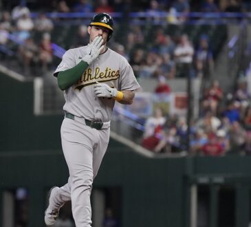Athletics catcher Jonah Heim raises a hand toward the stands while rounding the bases after a home run.