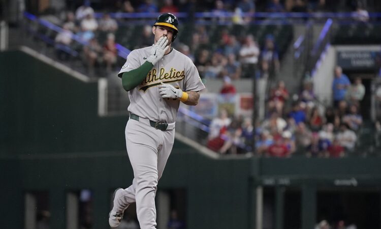 Athletics catcher Jonah Heim raises a hand toward the stands while rounding the bases after a home run.