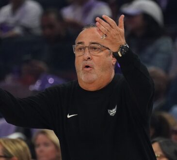 Dallas Wings head coach Jose Fernandez raises both hands as he reacts from the sideline.