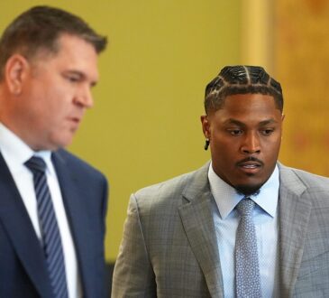 Green Bay Packers running back Josh Jacobs walks through a courtroom alongside his attorney.