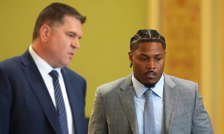 Green Bay Packers running back Josh Jacobs walks through a courtroom alongside his attorney.