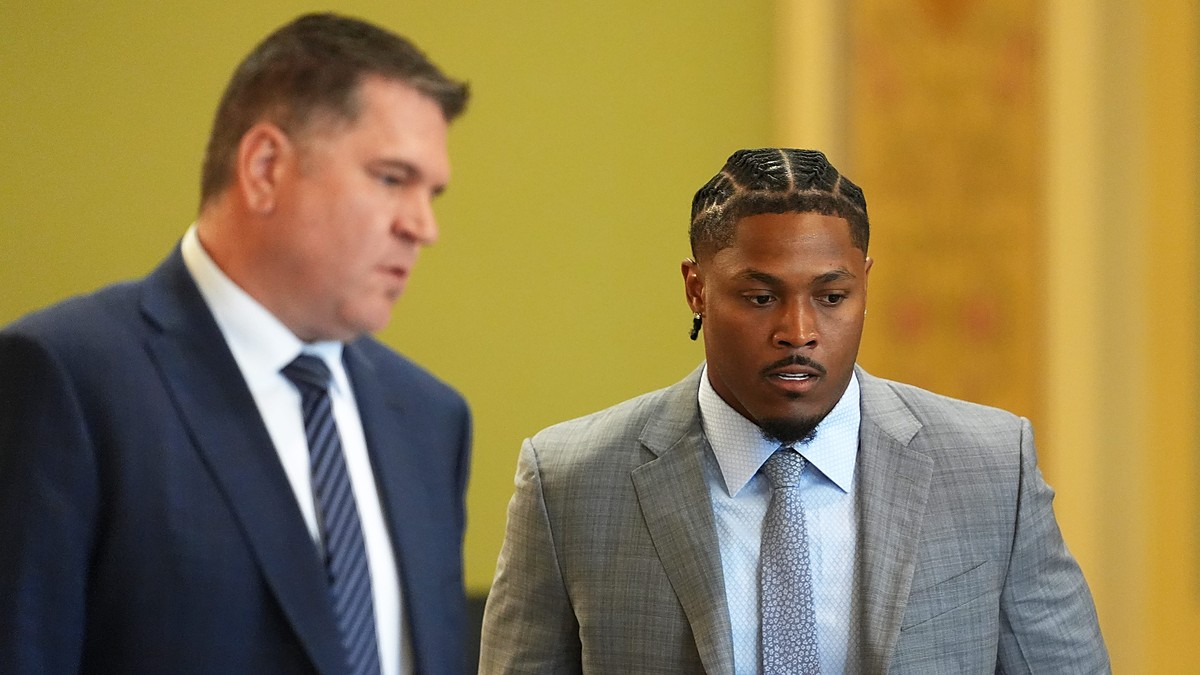 Green Bay Packers running back Josh Jacobs walks through a courtroom alongside his attorney.