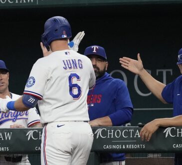 Texas Rangers third baseman Josh Jung high-fives manager Jared Schumaker and coaches at the dugout rail.