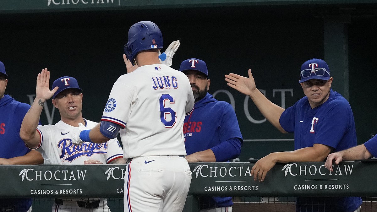 Texas Rangers third baseman Josh Jung high-fives manager Jared Schumaker and coaches at the dugout rail.