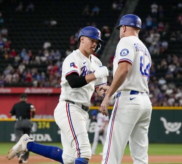 Texas Rangers third baseman Josh Jung fist bumps third base coach Corey Ragsdale while rounding the bases.