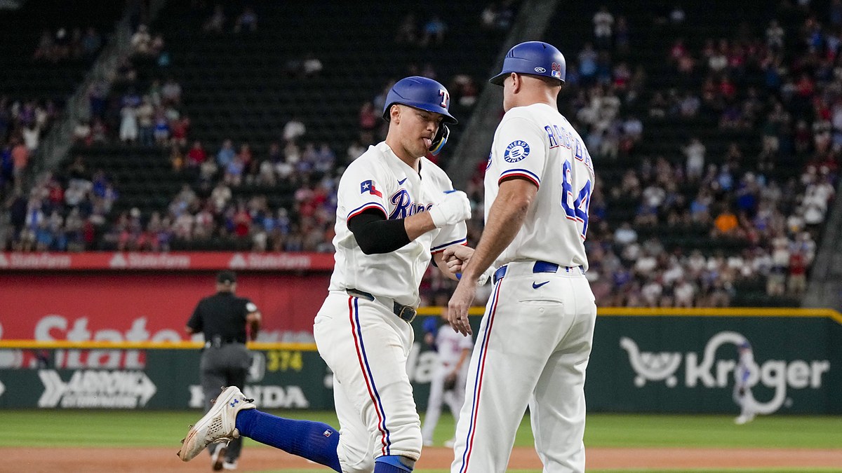 Texas Rangers third baseman Josh Jung fist bumps third base coach Corey Ragsdale while rounding the bases.