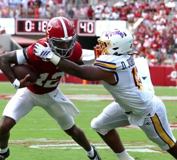Alabama Crimson Tide quarterback Keelon Russell, No. 12, is grabbed by East Carolina linebacker DJ Johnson Jr. while running with the ball.