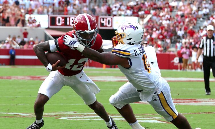 Alabama Crimson Tide quarterback Keelon Russell, No. 12, is grabbed by East Carolina linebacker DJ Johnson Jr. while running with the ball.