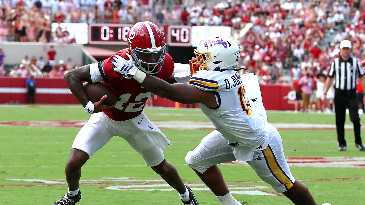 Alabama Crimson Tide quarterback Keelon Russell, No. 12, is grabbed by East Carolina linebacker DJ Johnson Jr. while running with the ball.