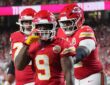 Kansas City Chiefs running back Kenneth Walker III gestures toward the camera as teammates join him after a touchdown.