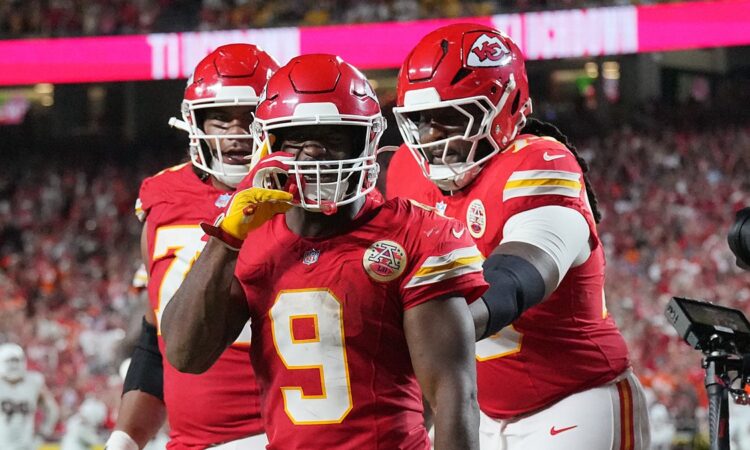 Kansas City Chiefs running back Kenneth Walker III gestures toward the camera as teammates join him after a touchdown.