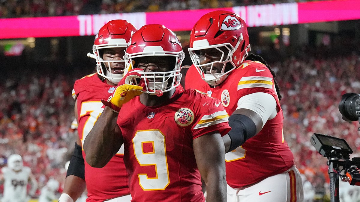 Kansas City Chiefs running back Kenneth Walker III gestures toward the camera as teammates join him after a touchdown.