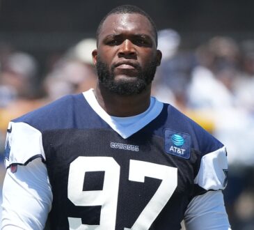 Dallas Cowboys defensive tackle Kenny Clark stands on the practice field in a No. 97 jersey at training camp.