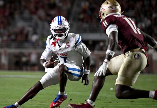 SMU Mustangs quarterback Kevin Jennings tucks the ball and cuts back as a Florida State defender closes in.
