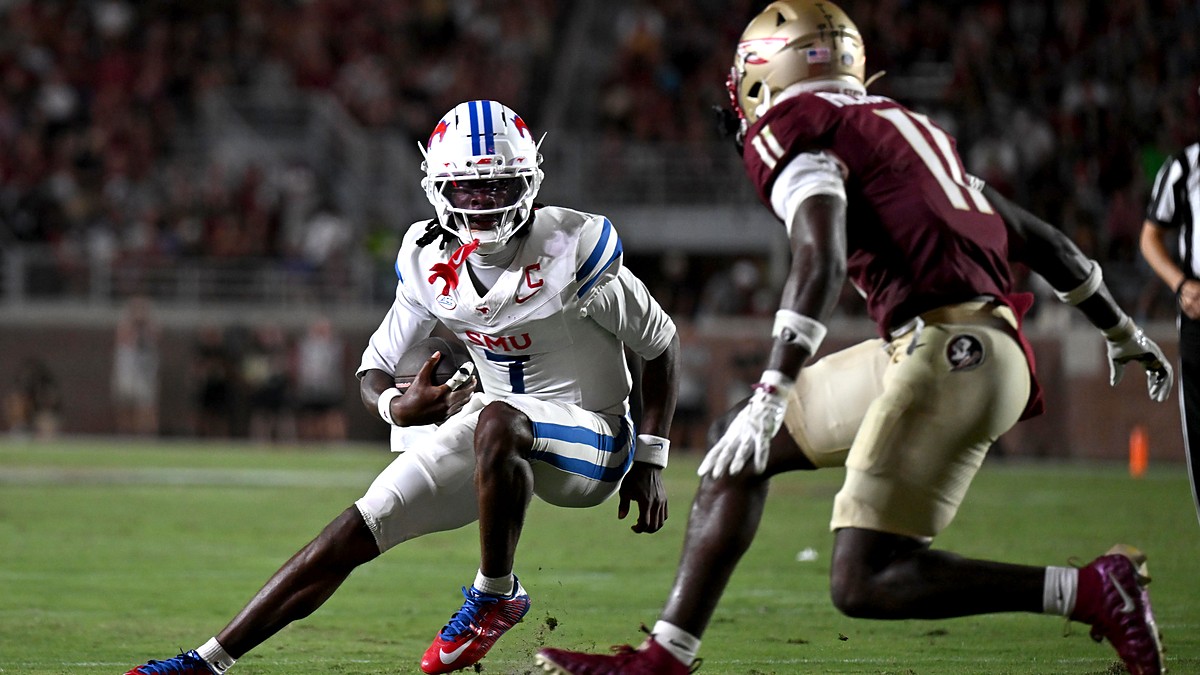SMU Mustangs quarterback Kevin Jennings tucks the ball and cuts back as a Florida State defender closes in.
