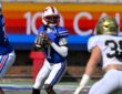 SMU quarterback Kevin Jennings drops back to pass with the ball at his chest as a UC Davis defender closes in.
