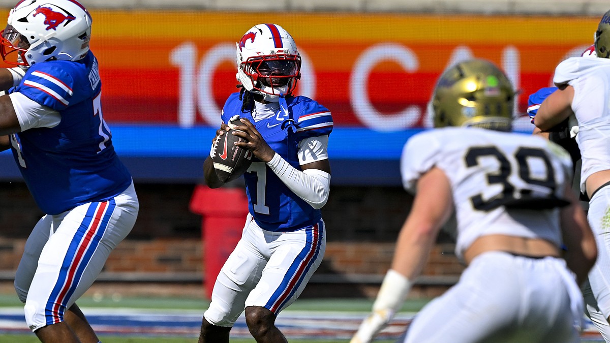 SMU quarterback Kevin Jennings drops back to pass with the ball at his chest as a UC Davis defender closes in.