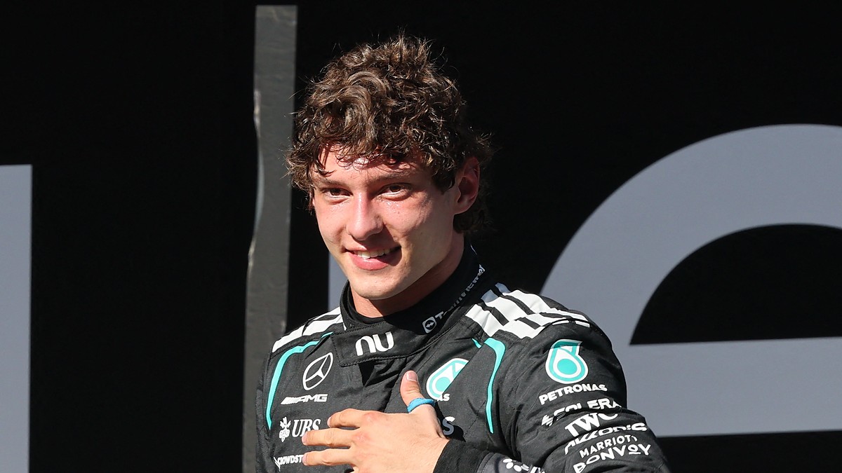Mercedes driver Andrea Kimi Antonelli smiles with his hand on his chest while wearing his race suit.