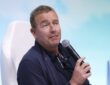 ESPN College GameDay analyst Kirk Herbstreit holds a microphone while speaking at a fan event.