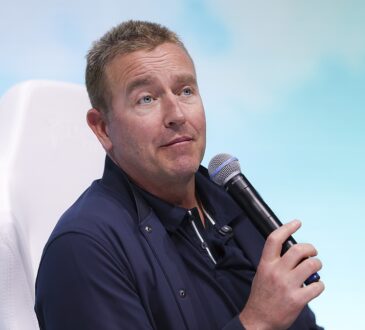 ESPN College GameDay analyst Kirk Herbstreit holds a microphone while speaking at a fan event.
