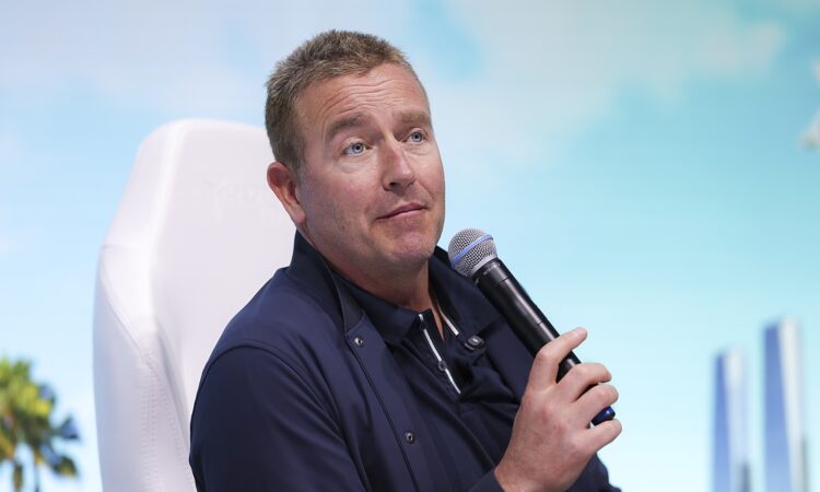 ESPN College GameDay analyst Kirk Herbstreit holds a microphone while speaking at a fan event.