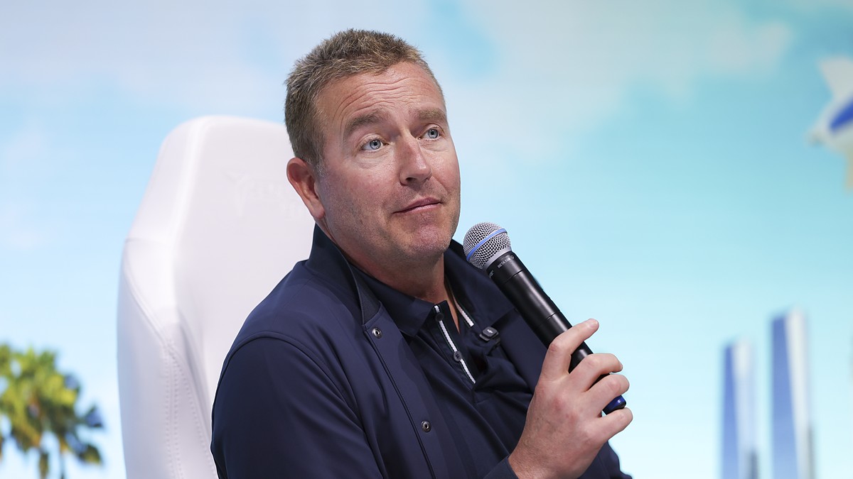 ESPN College GameDay analyst Kirk Herbstreit holds a microphone while speaking at a fan event.