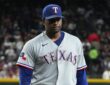 Texas Rangers pitcher Kumar Rocker walks off the field with a flat expression after the first inning.