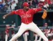 Texas Rangers right-hander Kumar Rocker, No. 80, strides toward the plate in a red Tejas jersey.